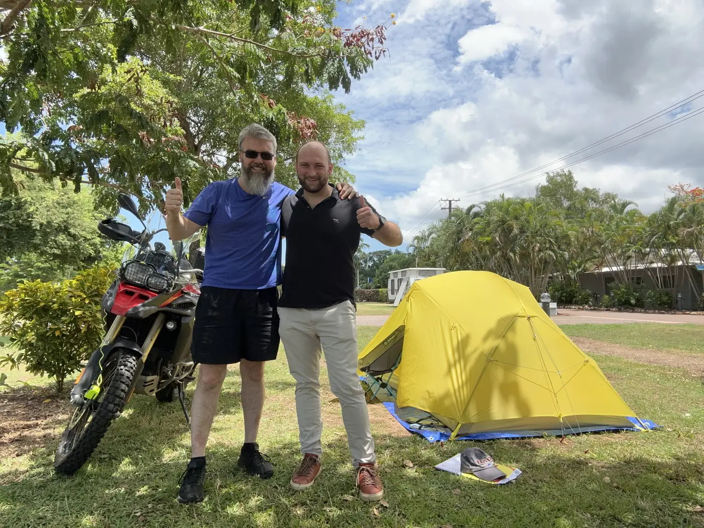 Bikes and a small tent at a campsite, with a fellow traveller nearby.