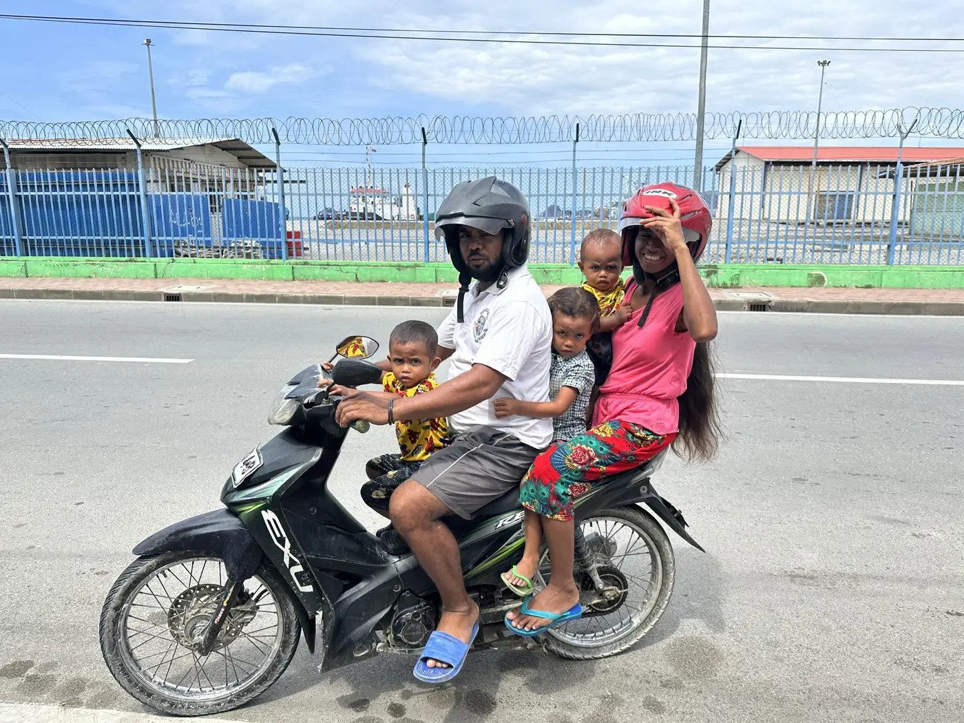 A family of several riding together on a single scooter in Timor-Leste.