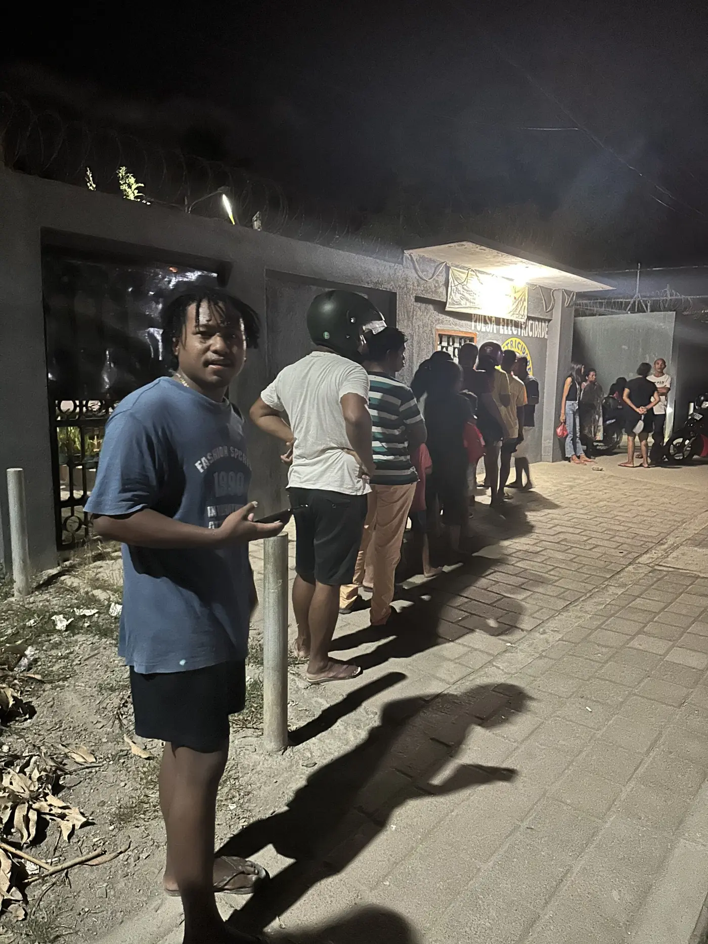 A companion (front) in queue for power — Timor-Leste.