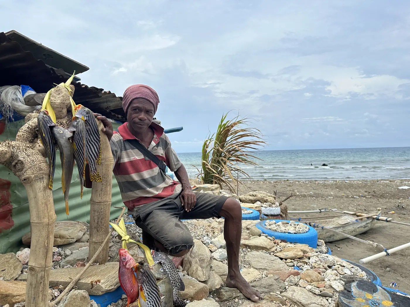 A local fisherman resting among his gear on a Timor-Leste beach.