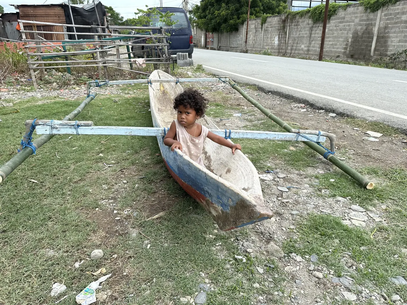 A young child paddling a small wooden canoe near the shore.