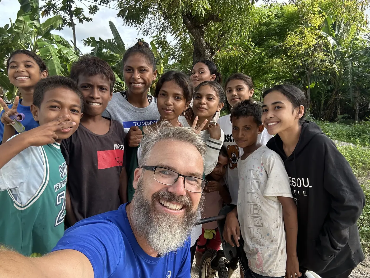 The traveller surrounded by a group of smiling local children on a roadside.