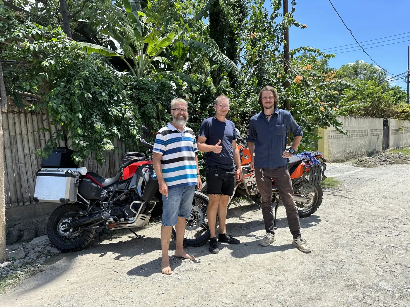 The traveller and two fellow riders standing with their loaded motorbikes on a Timor-Leste lane.