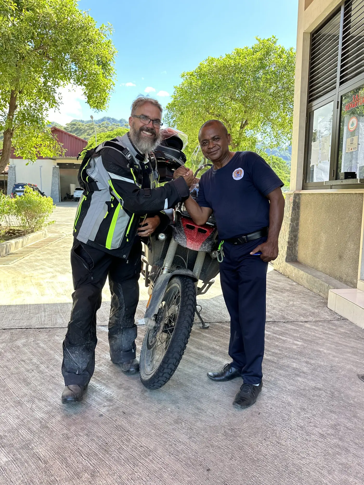 Border customs officers posing with the traveller and his motorbike.